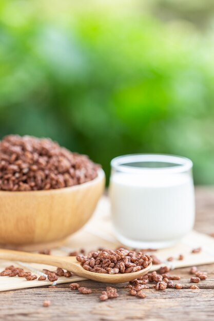 Cereal de desayuno, arroz inflado con cacao en un tazón y vaso de leche en la mesa de madera