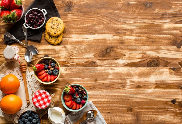 Cereal. Desayuno con muesli y frutas frescas en tazones sobre un fondo de madera rústica,