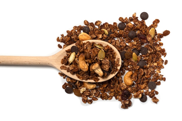 Cereal de granola de chocolate con nueces en una cuchara de madera. Aislado en el bacckground blanco.