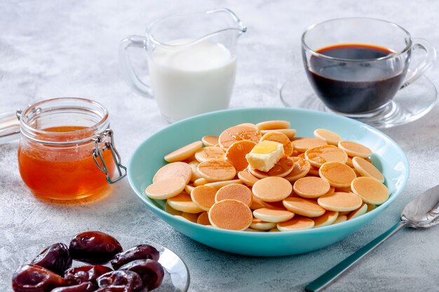 Cereal de panqueques con mantequilla y miel o jarabe de arce en un tazón