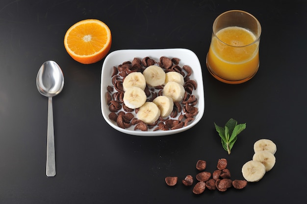 Cereales de chocolate con plátanos y jugo de naranja.