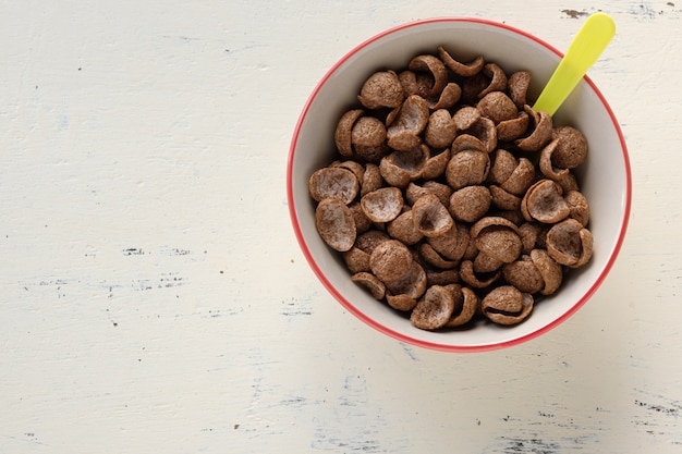 Cereales desayuno sabor a cacao en un tazón sobre fondo de madera con espacio de copia