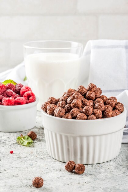Cereales para el desayuno, vaso de leche, frambuesas y menta en piedra gris
