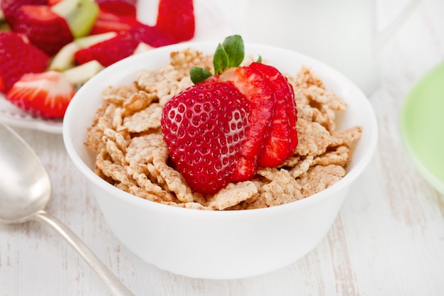 Cereales con fresa en un tazón con cuchara.