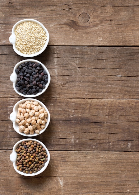 Cereales y legumbres en tazones sobre una mesa de madera con vista superior del espacio de copia en papel