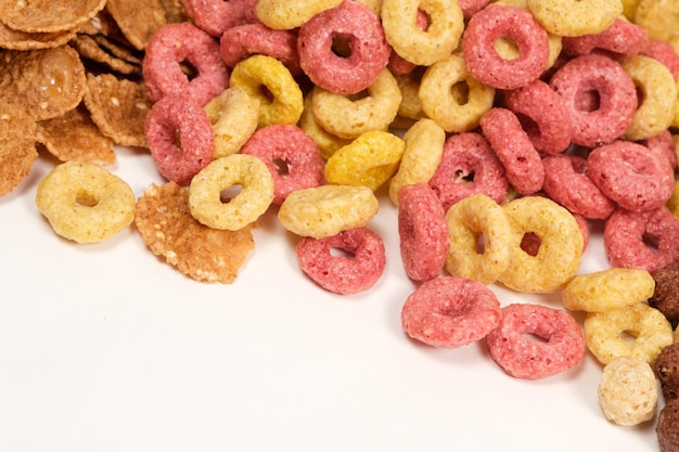 Cereales de maíz en forma de anillos multicolores sobre un fondo blanco.