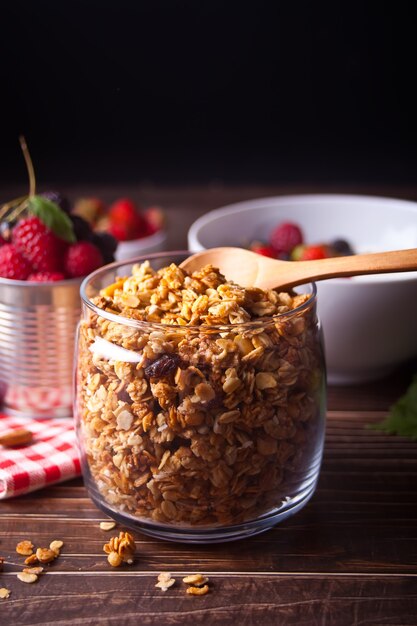 Cereales de muesli de granola de avena saludables en un frasco con bayas frescas