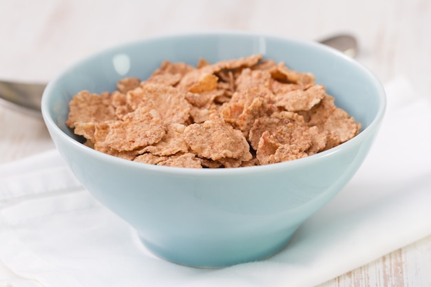 Cereales en un tazón azul sobre mesa de madera blanca