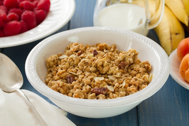 Foto cereales en un tazón blanco con leche y frutas.