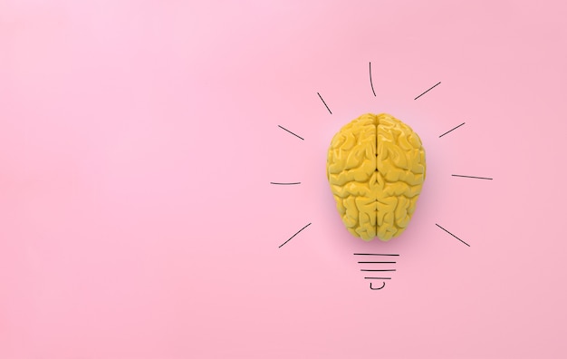 Cerebro amarillo sobre fondo rosa, idea de bombilla de concepto con dibujo a lápiz. Espacio para texto. Representación 3D.