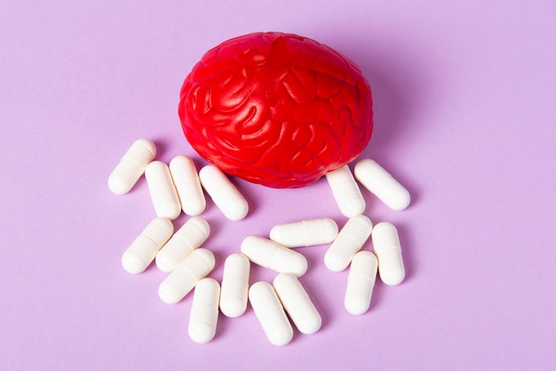 Cérebro vermelho em um fundo rosa com comprimidos brancos. Algumas pílulas para o cérebro.