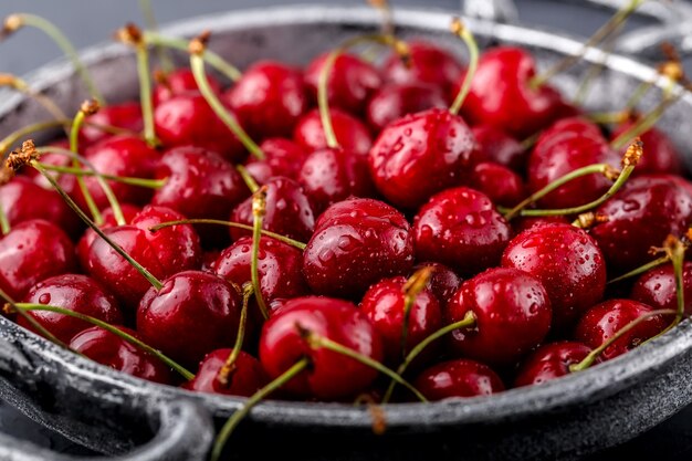 Foto cereja - punhado de cerejas maduras e suculentas em uma tigela de metal sobre uma mesa