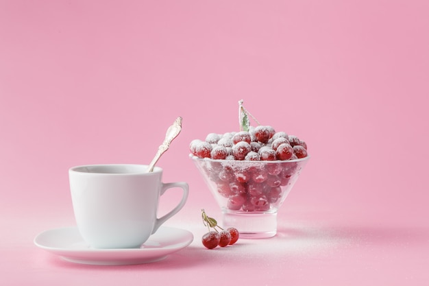 Cereja selvagem em um prato com uma caneca de café em uma rosa