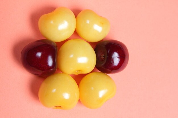 Cerejas amarelas e vermelhas suculentas doces em um fundo rosa Vista de cima Conceito de comida vegetariana Closeup