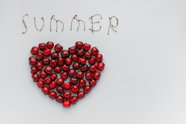 Cerejas de bagas vermelhas em forma de coração e texto verão