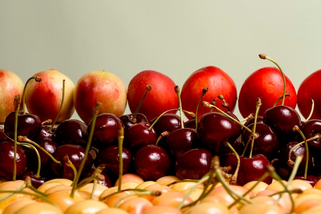 Cerejas e pêssegos amarelos vermelhos no balcão com um fundo claro agradável