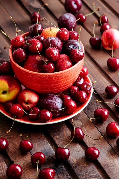 Cerejas frescas e nectarina na mesa de madeira.