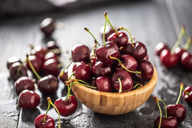 Cerejas frescas lavadas em água limpa em uma tigela e espalhadas por toda parte.