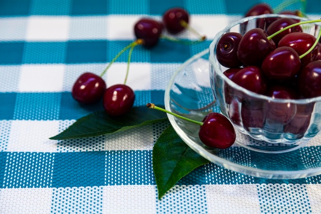 Cerejas maduras em uma caneca transparente em um guardanapo xadrez. Natureza morta com frutas deliciosas.