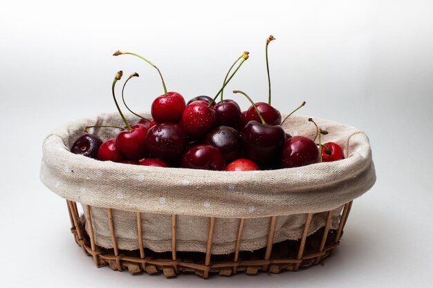 Cerejas maduras em uma cesta em um fundo branco