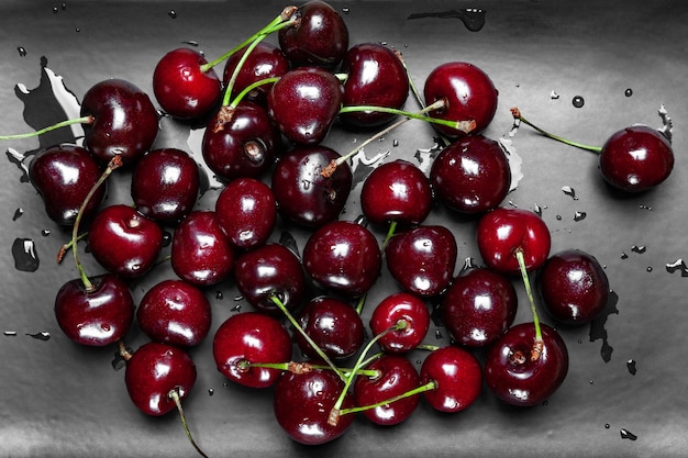 Cerejas maduras suculentas molhadas em uma placa preta Vista superior cerejas frescas molhadas com gotas de água