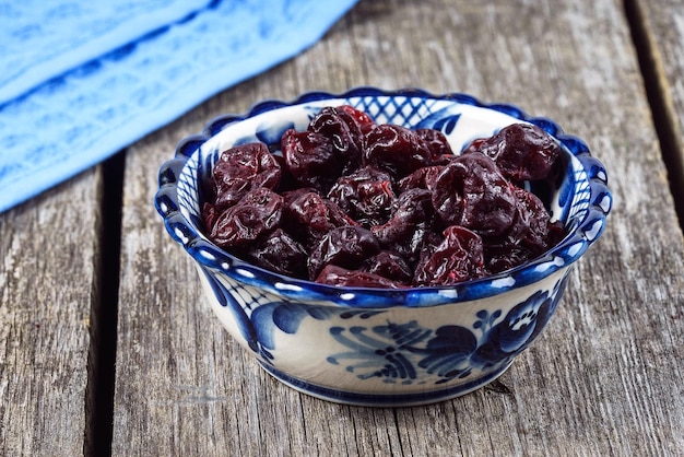 Cerejas secas em um prato azul sobre uma mesa de madeira em estilo rústico