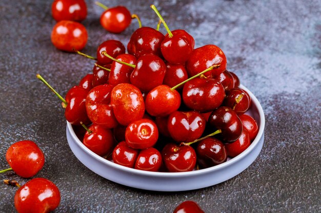 Cerejas vermelhas doces em um prato na superfície escura