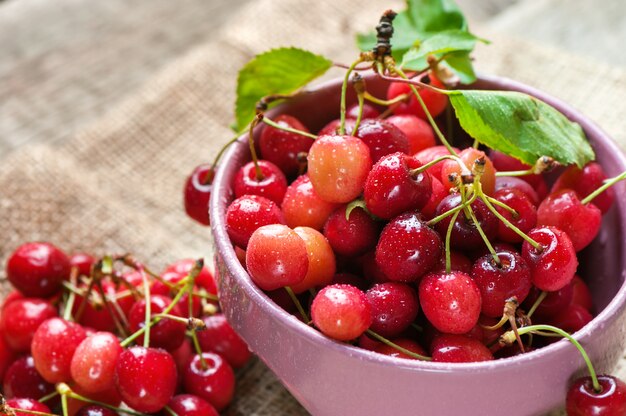 Cerejas vermelhas em uma tigela rosa na madeira