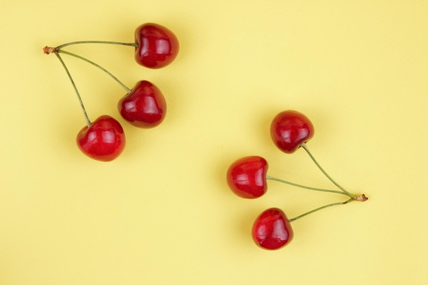 Cerejas vermelhas suculentas em um fundo amarelo Conceito de comida saudável Closeup de bagas doces
