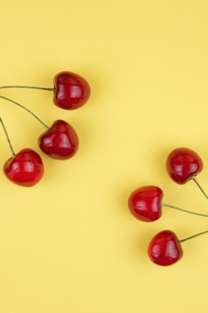 Cerejas vermelhas suculentas em um fundo amarelo Conceito de comida saudável Closeup de bagas doces