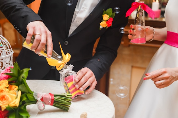 ceremonia de arena que se realiza en la boda. Manos de la novia sosteniendo un jarrón con arena de colores durante la fiesta de bodas