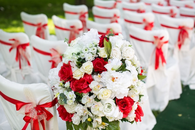 Ceremonia de boda al aire libre con sillas blancas y cintas rojas