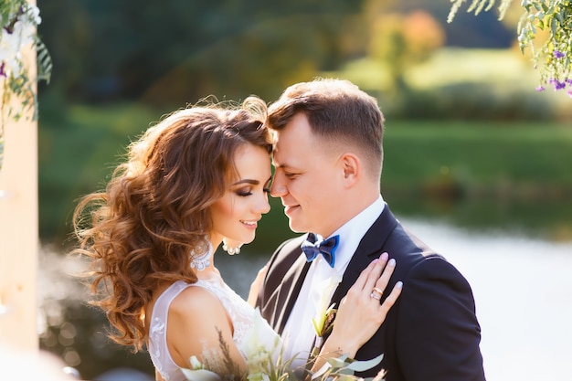 Ceremonia de boda con estilo creativo elegante rizado novia y el novio al aire libre en el fondo del lago