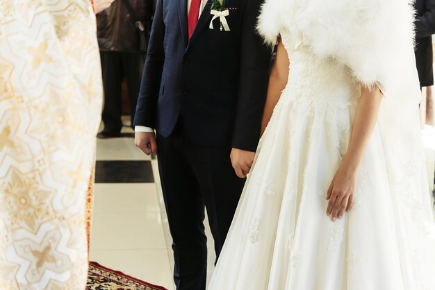 Ceremonia de boda de feliz y elegante novia rubia y elegante novio tomándose de la mano en la antigua iglesia