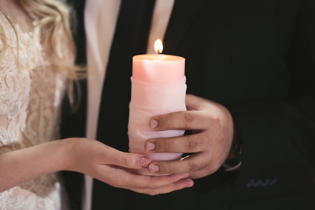 Ceremonia de boda, parafernalia, la novia y el novio sostienen una vela grande en la mano