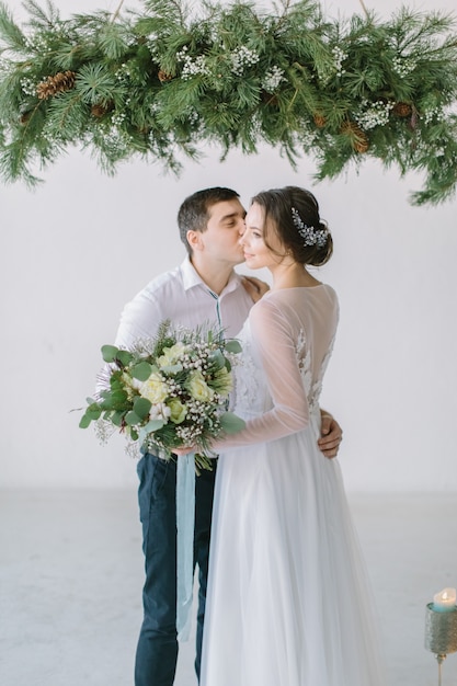 Ceremonia de boda en sala blanca y clara decorada con pino, flores y velas