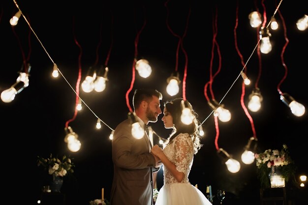 La ceremonia nupcial nocturna. La novia y el novio mirando el uno al otro en el fondo