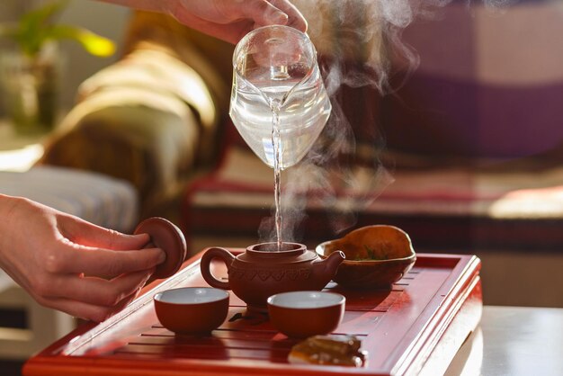 La ceremonia del té. La mujer vierte agua caliente en la tetera con té