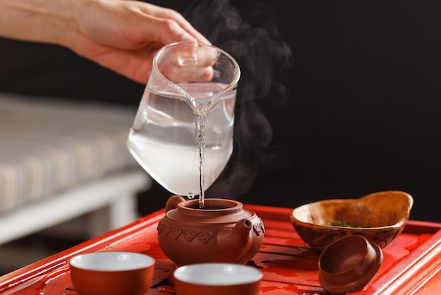 La ceremonia del té. La mujer vierte agua caliente en la tetera con té