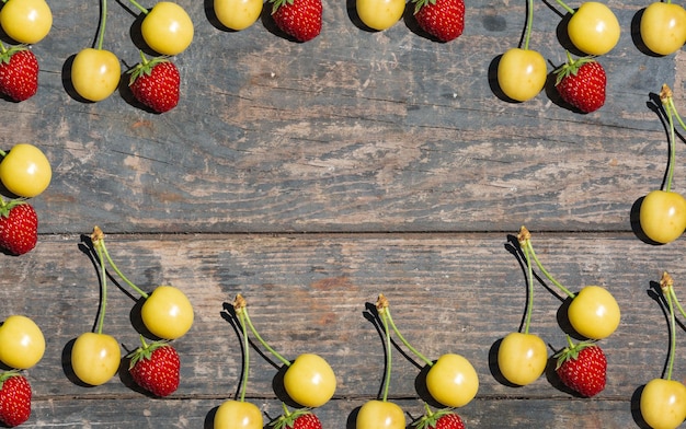 Cereza amarilla y fresa roja en tableros de textura de madera Frutas de huerta de jardinería rural