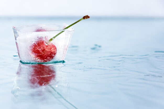 La cereza se congela en un cubo de hielo