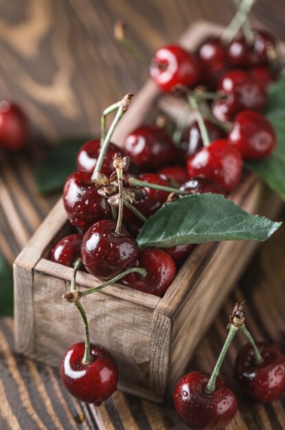 Cereza fresca con gotas de agua sobre la mesa de madera rústica.