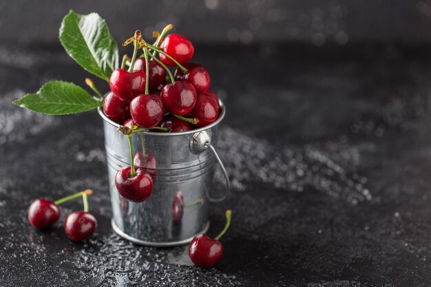 Cereza fresca con gotas de agua sobre la mesa oscura.