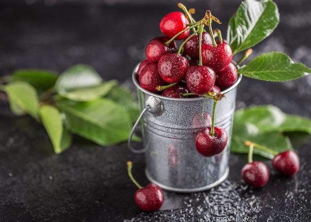 Cereza fresca con gotas de agua sobre la mesa oscura.