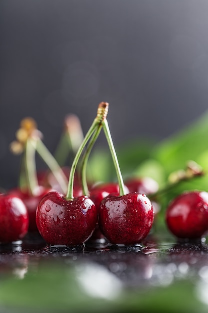 Cereza fresca con gotas de agua sobre la mesa oscura.