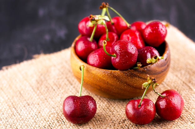 Cereza fresca en la mesa de madera negra. Bayas maduras dulces en gotas de agua