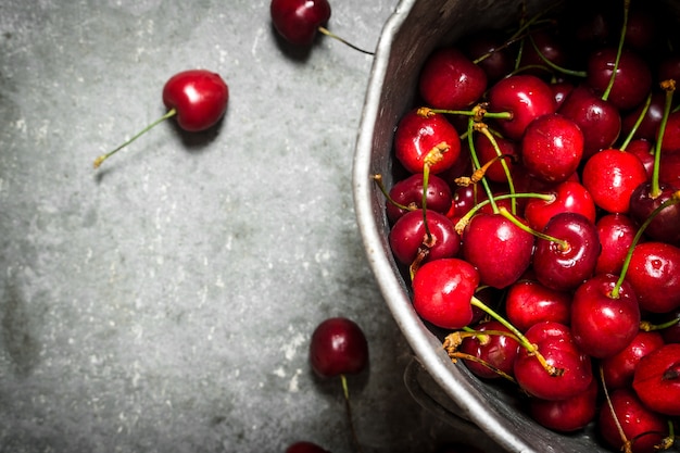 Cereza fresca en la olla vieja. Sobre la mesa de piedra.