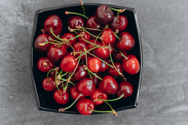 Cereza de jardín fresca en plato negro sobre fondo oscuro