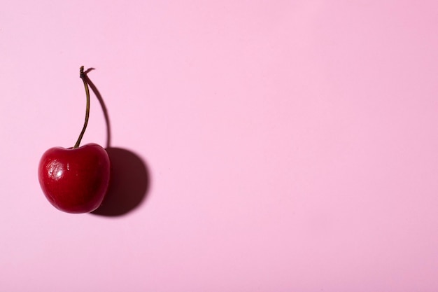 Cereza plana yacía sobre un fondo rosa