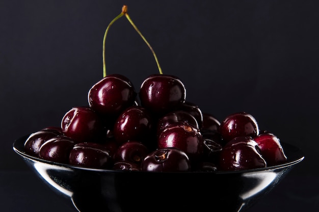 Cereza en un plato negro sobre oscuro